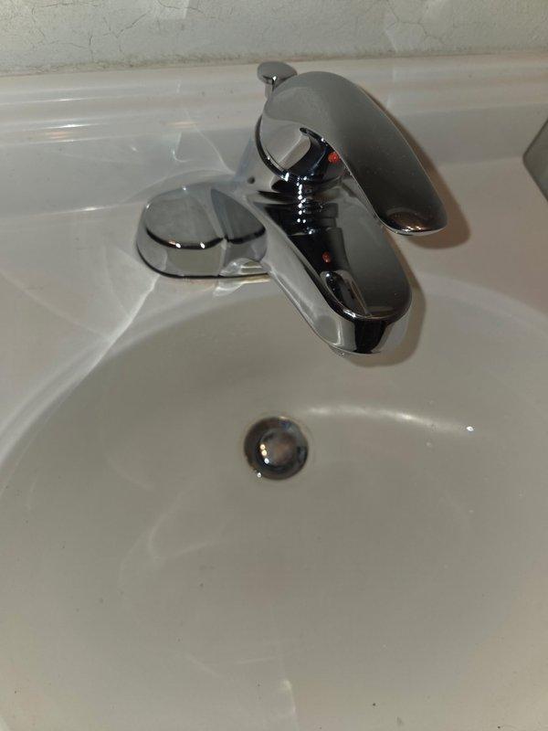 Inspected bathroom sink and faucet fixture. Documented condition of chrome single-handle faucet and white porcelain basin. Noted minor wall cracking near backsplash area. No active issues observed with plumbing components.