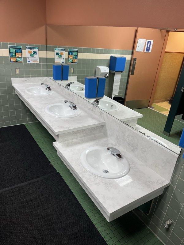Conducted inspection of public restroom facilities including examination of three automatic faucet sinks with marble-patterned countertop and wall-mounted urinal system. All plumbing fixtures were verified to be in proper working condition with no visible leaks or functional issues. Confirmed proper operation of flush mechanisms and water supply systems throughout the facility.