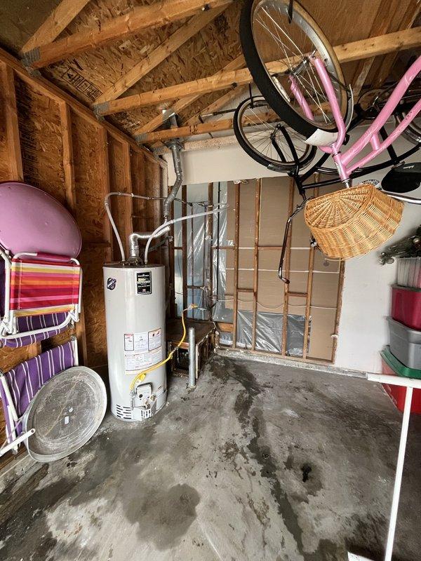 Conducted inspection of basement utility area with visible water damage on concrete floor. Examined unfinished walls with exposed wooden framing and partial insulation to assess potential mold development around water heater and HVAC system. Documented conditions with photographs, noting water stains and possible moisture intrusion requiring remediation to prevent further structural damage and mold growth.