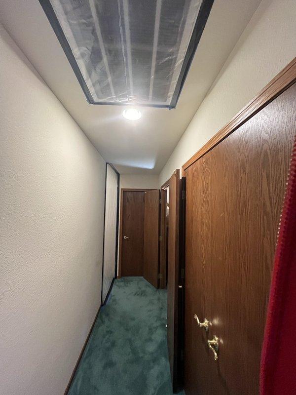 Conducted comprehensive inspection of residential property, identifying water damage along interior hallway and adjacent wall sections. Documented evidence of water intrusion with visible staining patterns on the greenish-blue textured wall surface and potential structural concerns where moisture had affected the wooden framing elements. Performed remediation procedures and recommended preventative measures to address the underlying moisture source.