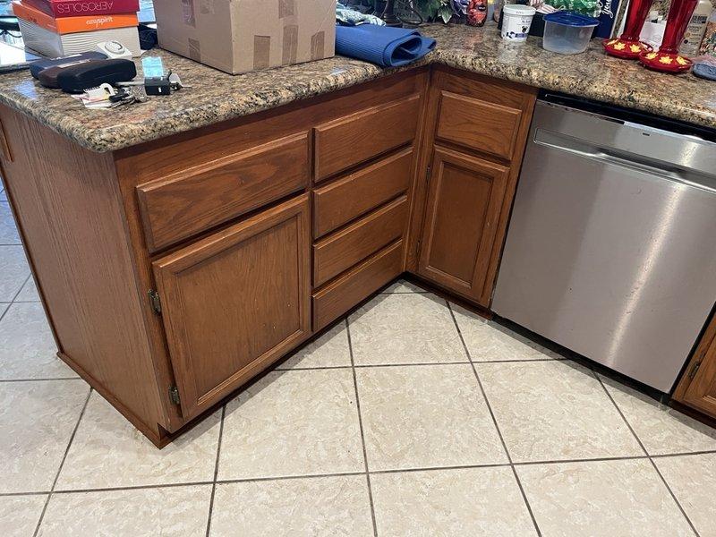 Conducted inspection of kitchen cabinetry and accessed ceiling panel to examine plumbing system. Documented copper pipe configuration with brass valve at junction point and photographed both the kitchen area and plumbing access panel for service records.