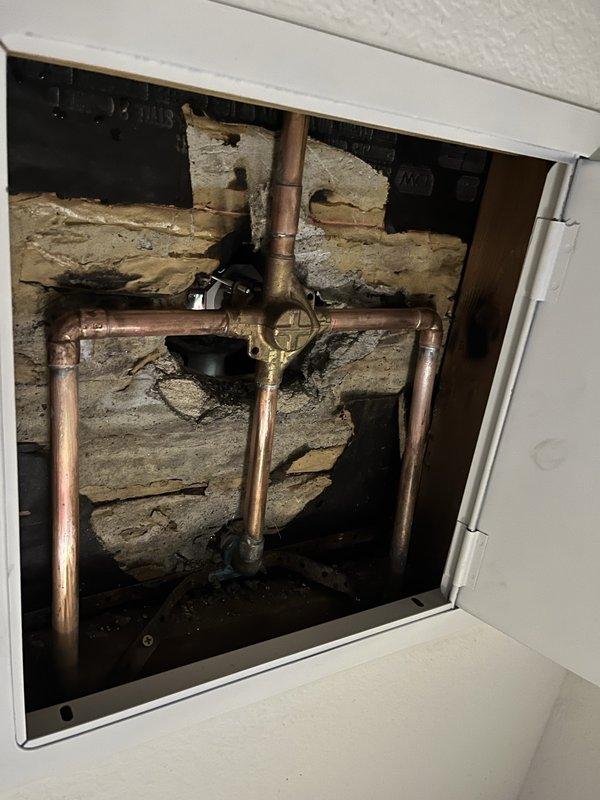 Conducted inspection of kitchen cabinetry and accessed ceiling panel to examine plumbing system. Documented copper pipe configuration with brass valve at junction point and photographed both the kitchen area and plumbing access panel for service records.