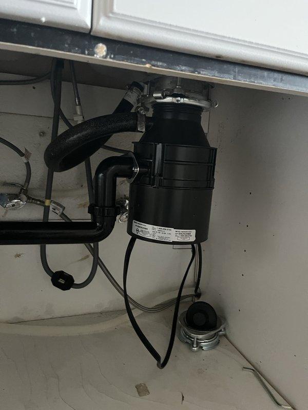 Performed inspection and documentation of installed garbage disposal system. Unit appears to be properly mounted under sink with standard plumbing connections including P-trap assembly and drain pipes. Noted minor water damage and staining on cabinet floor that may require future attention.