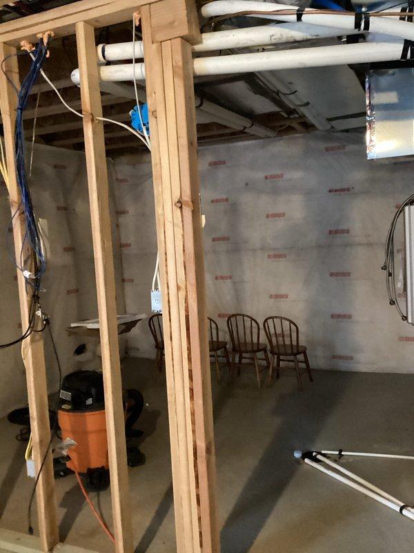 Conducted assessment of unfinished basement requiring electrical work. Evaluated space for installation of approximately 8 new outlets and bringing 2 existing outlets up to code. Documented requirements for recessed lighting throughout basement and sconce fixtures in bathroom area. Basement currently has exposed framing with visible electrical wiring hanging from joists, requiring complete wiring solution before finishing work proceeds.