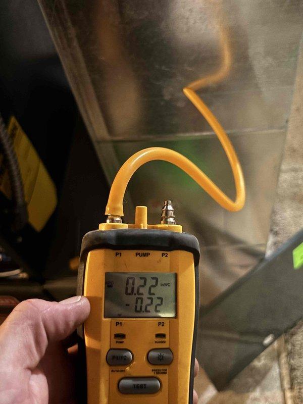 Responded to heating system operating intermittently with warm air output issues on a one-year-old furnace unit. Upon inspection, identified system overheating caused by restricted airflow due to dirty filter and significantly compromised ductwork. Performed diagnostic pressure testing using digital manometer, measuring static pressure readings of 0.22 inWC, confirming excessive restriction in the duct system. Documented visible ductwork damage and restriction issues in basement installation. Recommended comprehensive duct cleaning service to restore proper airflow and system performance, preventing future overheating conditions and ensuring efficient operation of the heating system.