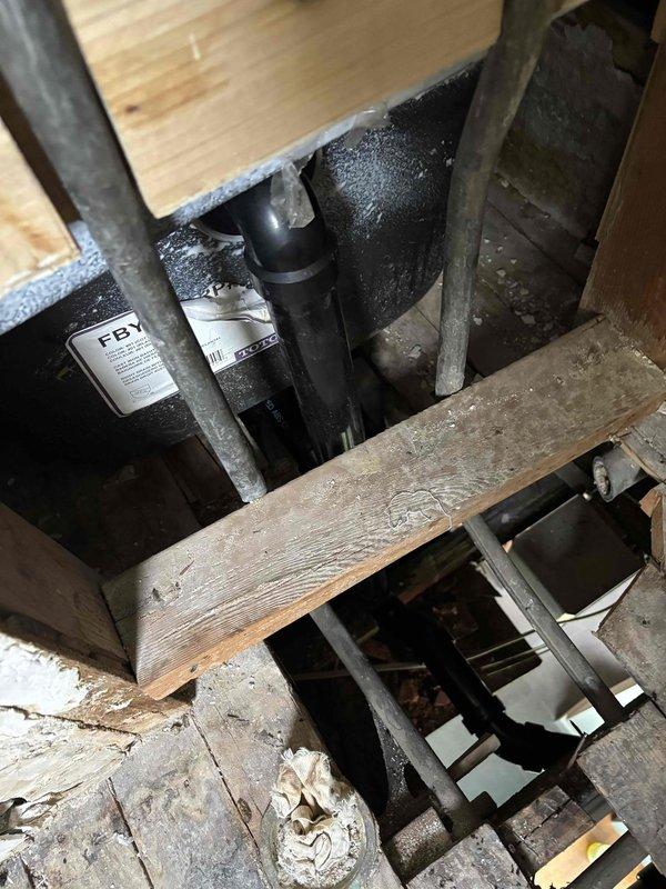 Completed full bathroom group drainage replacement involving access through wood panel ceiling from below. Removed existing toilet drain, complete tub waste and overflow assembly, drum trap, and deteriorated sink drainage piping. Installed new ABS plastic individual wye fittings for each fixture to ensure proper drainage and code compliance. Installed new tub waste and overflow with p-trap and chrome drain assembly for bathtub. Set new toilet flange and adapted connections to existing serviceable piping sections for sink drain. All horizontal drain runs completed as planned without requiring additional vertical piping modifications.