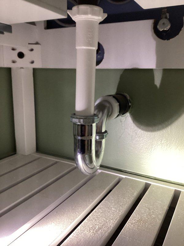 Completed annual plumbing maintenance membership inspection including comprehensive water heater evaluation and flush service. Inspected under-sink drain assembly featuring white PVC tailpiece connected to chrome P-trap with proper wall drain connection, verifying all connections were secure and leak-free. Examined bathroom plumbing fixtures including tub/shower chrome control valve, tub spout, and drain assembly, confirming proper operation and no visible leaks. Water heater inspected and flushed per maintenance protocol; unit is approximately one year old and operating within normal parameters. All plumbing systems found in good working condition with no immediate repairs required.