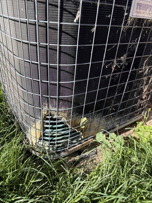 Performed estimate on 4-5 year old residential air conditioning condenser unit reported as non-operational. Previous technician from another company had deemed unit non-repairable. Upon inspection, condenser exhibited extensive corrosion and damage to exterior coil and components due to prolonged pet urine exposure. Visual assessment confirmed significant deterioration of condenser coil fins, protective mesh guard showing weathering, and base components displaying heavy contamination and corrosion. Unit positioned on ground-level pad against building exterior with adequate clearance but showing signs of environmental damage and debris accumulation around base. Recommended condenser replacement as most viable solution given extent of corrosion damage to critical components and age of equipment. Presented replacement options to homeowner with emphasis on condenser-only replacement per customer preference, as remaining system components were recently installed. Customer expressed interest