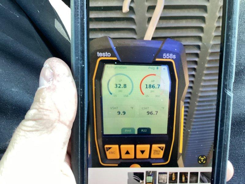 Responded to cooling efficiency concern on residential air conditioning system over 10 years old. Performed comprehensive system diagnostics using digital testing equipment to measure temperature differential and system pressures. Measurements indicated supply air temperature of 22.0°F at the register and system parameters showing 32.8 and 186.7 readings on refrigerant gauges, with additional diagnostics showing 9.9 and 96.7 values. Evaluated outdoor condensing unit in backyard and indoor air handler in downstairs storage room. Documented system performance with diagnostic readings to assess cooling capacity and overall system operation.
