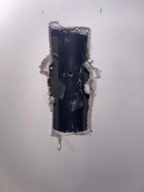 Responded to gas leak emergency caused by accidental wall penetration during TV mounting attempt. Upon arrival, confirmed gas supply had been shut off as a safety precaution, leaving property without gas service to water heater and HVAC system. Inspected damaged area and located compromised gas line within wall cavity. Assessed extent of damage to black gas pipe and surrounding drywall. Evaluated utility closet containing water heater, pressure tank, and associated plumbing infrastructure to verify system integrity and connections. Documented damage with photographs showing wall penetration and mechanical equipment for repair planning and restoration of gas service.