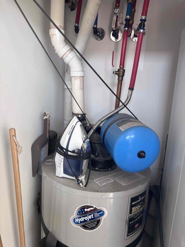 Responded to gas leak emergency caused by accidental wall penetration during TV mounting attempt. Upon arrival, confirmed gas supply had been shut off as a safety precaution, leaving property without gas service to water heater and HVAC system. Inspected damaged area and located compromised gas line within wall cavity. Assessed extent of damage to black gas pipe and surrounding drywall. Evaluated utility closet containing water heater, pressure tank, and associated plumbing infrastructure to verify system integrity and connections. Documented damage with photographs showing wall penetration and mechanical equipment for repair planning and restoration of gas service.
