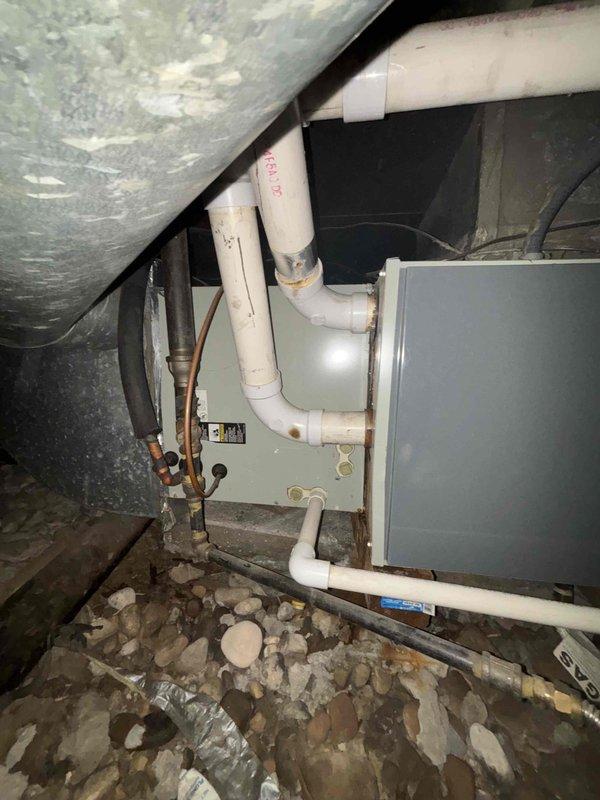 Conducted system evaluation of residential HVAC air handler unit located in crawl space. Inspected air handler, refrigerant lines, PVC condensate drainage system, and ductwork connections. Documented equipment condition with photographs showing proper installation of drainage piping, copper refrigerant lines, and flexible conduit connections. Verified system operational status and confirmed all components functioning as designed with no immediate service needs identified.