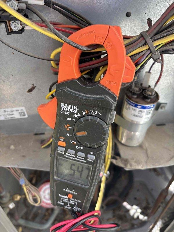 Performed diagnostic evaluation on 16-year-old residential air conditioning unit with suspected refrigerant leak and unusual odor complaint. Accessed electrical compartment and conducted comprehensive electrical testing using digital clamp meter. Measured amperage draw at compressor circuit, recording 54 amps, and verified system voltage at 336.4 volts to assess compressor performance and electrical integrity. Inspected capacitor, wiring connections, and control panel components for signs of failure or degradation. Documented findings with diagnostic photos showing electrical measurements and internal component condition to support repair recommendations.