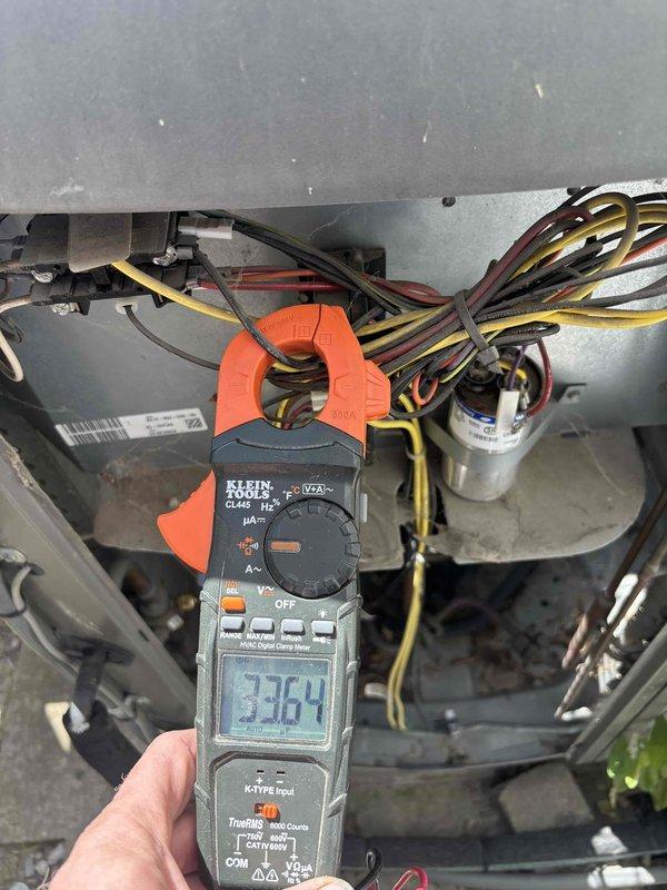 Performed diagnostic evaluation on 16-year-old residential air conditioning unit with suspected refrigerant leak and unusual odor complaint. Accessed electrical compartment and conducted comprehensive electrical testing using digital clamp meter. Measured amperage draw at compressor circuit, recording 54 amps, and verified system voltage at 336.4 volts to assess compressor performance and electrical integrity. Inspected capacitor, wiring connections, and control panel components for signs of failure or degradation. Documented findings with diagnostic photos showing electrical measurements and internal component condition to support repair recommendations.