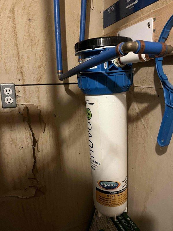 Completed membership plumbing inspection at residential property with focus on tankless water heater system located in lower level. Inspected whole-house water filtration system including Craig's Aqua filter canister, blue PEX supply lines, and associated plumbing connections. Evaluated filter condition per homeowner request regarding potential replacement needs. Documented existing water staining on wall below filtration system and verified proper operation of water softener/filtration equipment. All plumbing connections, mounting hardware, and system components inspected for proper function and potential maintenance requirements.