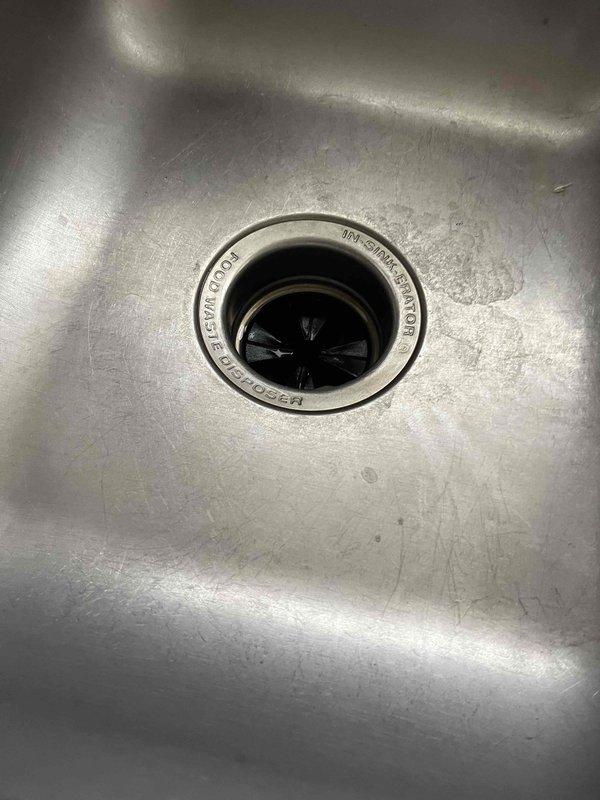 Responded to kitchen garbage disposal failure with reported leaking, grinding issues, and smoking before complete operational failure. Upon inspection, found disposal unit showed signs of significant wear, corrosion, and internal damage consistent with age and deterioration. Documented existing conditions including damaged motor housing and evidence of electrical failure. Evaluated disposal system and provided recommendations for replacement due to safety concerns and extent of component damage.