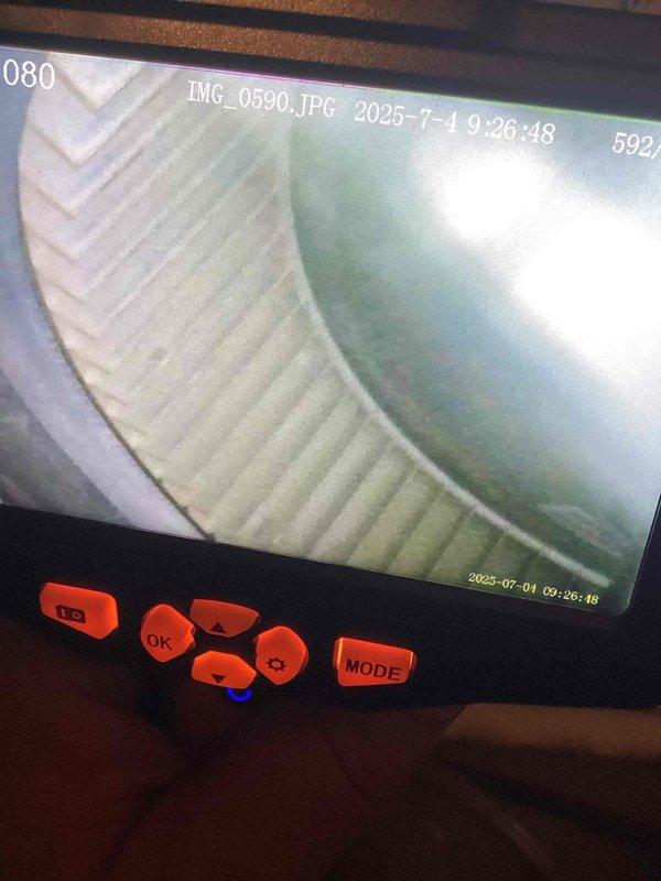 Responded to service call for HVAC system experiencing high-pitched whistling noise and short cycling on a six-year-old residential unit. Performed thorough inspection of air handler and ductwork components using borescope camera to identify source of noise. Discovered significant accumulation of dust and debris on lower blower motor assembly and heat exchanger fins. Inspected secondary heat exchanger with camera and confirmed it was clean with no damage or deterioration. Documented debris buildup on metallic fins and refrigerant lines with photos showing brown and tan material collected between components. Recommended thorough cleaning of affected components rather than replacement, as all parts were structurally sound and operational.