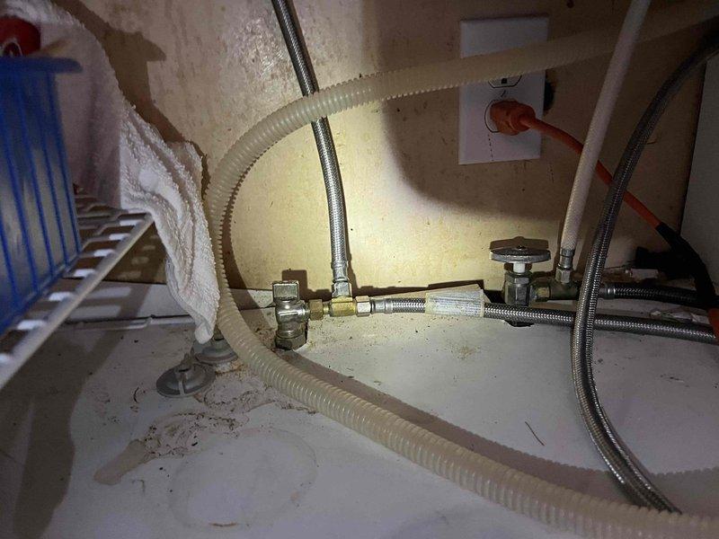 Responded to reported leak under kitchen sink initially suspected to be from copper solder fitting. Upon inspection, diagnosed actual source as deteriorated galvanized kitchen drain line showing active water seepage. Assessed plumbing configuration in utility space beneath sink area, including supply lines, shut-off valves, and drain assembly. Documented existing conditions of aged galvanized drain piping and surrounding plumbing infrastructure for repair recommendations.