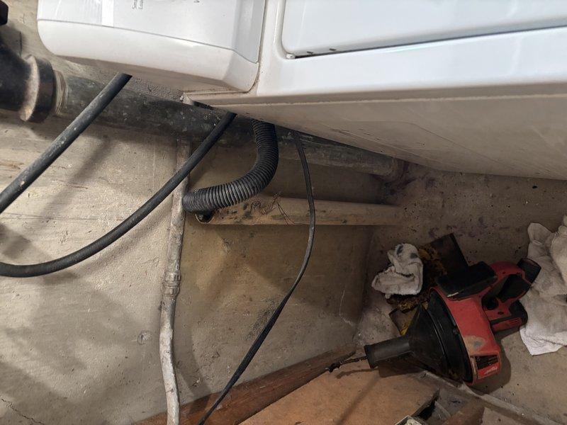 Responded to washing machine drain issue in basement. Upon inspection, found the washing machine discharge hose was not properly draining into the standpipe, causing drainage problems. Rerouted and secured the drain connection to ensure proper water flow from the washing machine into the drainage system, resolving the improper drainage condition.