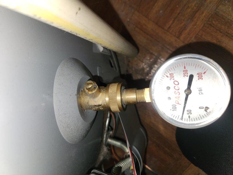 Completed comprehensive Green Shield membership plumbing inspection including radiant heating boiler system evaluation and assessment of 7-year-old tanked water heater located in basement. Inspected boiler operating pressure at 250 PSI and examined all plumbing connections, identifying deteriorated flexible supply line with significant mineral buildup and moisture accumulation requiring attention. Documented floor drain in shower area requiring augering service to clear blockage and restore proper drainage function.