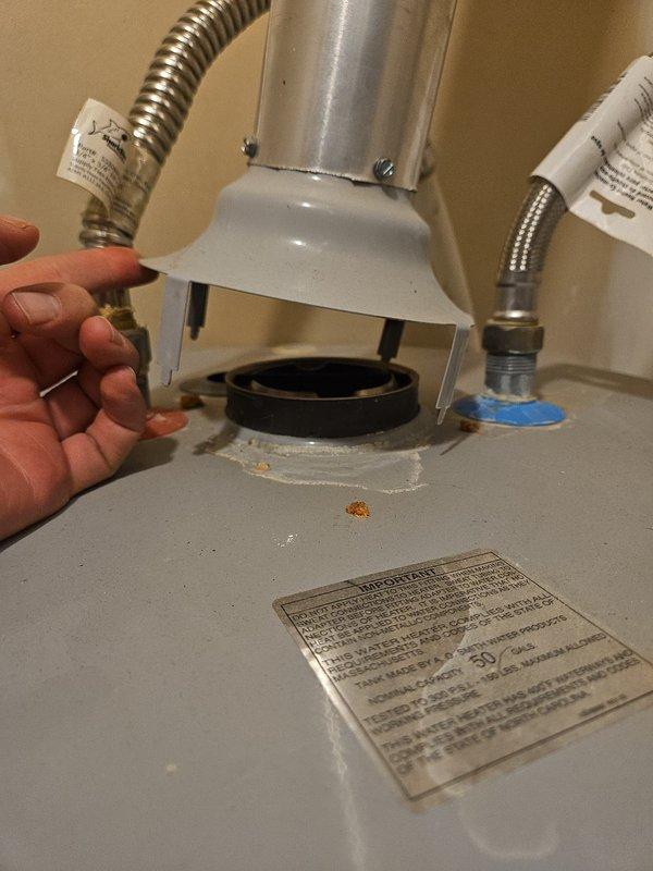 Secured the vent hood assembly to the top of a 2019 tanked water heater, ensuring proper connection with the draft diverter and verifying the gasket seal was intact. Addressed the hot side flexible connector by cleaning mineral deposits and residue from the fitting and connection point. Confirmed all connections were tight and properly sealed to prevent future leaks or draft issues.