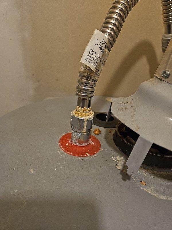 Secured the vent hood assembly to the top of a 2019 tanked water heater, ensuring proper connection with the draft diverter and verifying the gasket seal was intact. Addressed the hot side flexible connector by cleaning mineral deposits and residue from the fitting and connection point. Confirmed all connections were tight and properly sealed to prevent future leaks or draft issues.