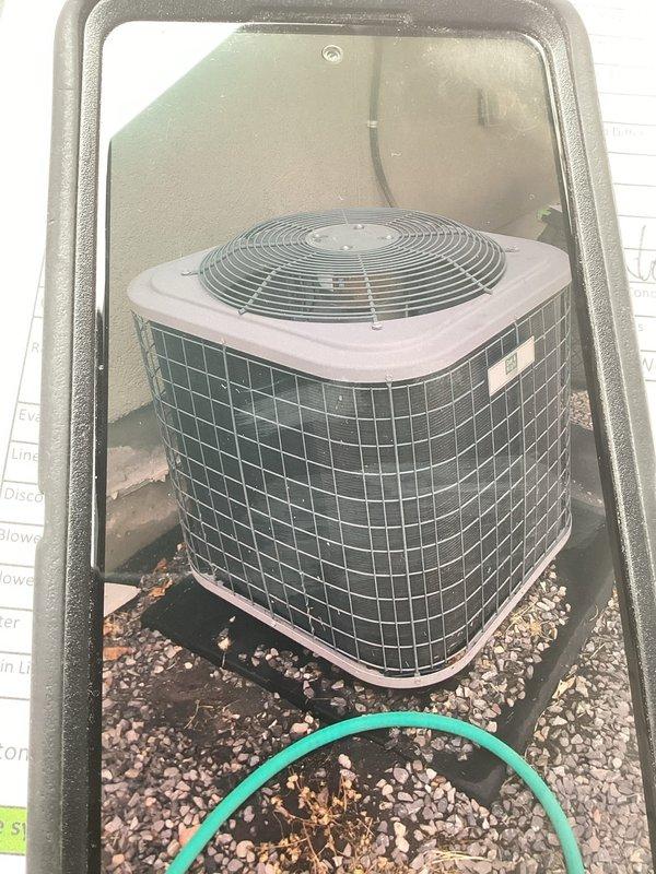 Responded to no-cooling complaint on 2019 residential central air conditioning system. Upon arrival, located outdoor condenser unit on gravel pad against building exterior. Performed diagnostic evaluation of system operation. Accessed electrical compartment and inspected internal components including capacitor, contactor relay, and associated wiring connections. Documented equipment condition with photographs of condenser unit exterior and electrical compartment showing capacitor, wire connections with wire nuts, and relay assembly. Unit found running but failing to provide adequate cooling to conditioned space.