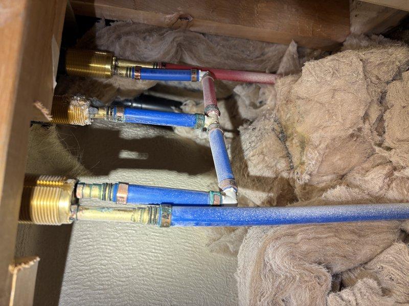 Responded to reported leak in master bathroom originating from bathtub area and manifesting under baseboard. Accessed plumbing infrastructure through attic/crawl space and inspected PEX water supply lines, compression fittings, and brass connectors serving the bathtub fixture. Replaced defective fittings and connections on blue PEX supply lines to eliminate leak source. Verified all chrome dual-handle faucet connections at tub surround were properly sealed and operational upon completion.