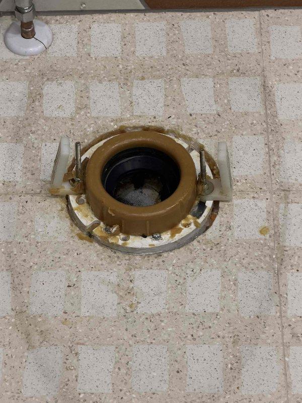Responded to callback for toilet leak at base following bidet installation. Upon inspection, found deteriorated wax ring seal and compromised toilet flange connection causing water seepage onto tile floor. Removed toilet to access flange assembly, which showed signs of age and wear with visible discoloration and residue buildup around mounting area. Replaced wax ring seal with new unit and reinstalled toilet, ensuring proper alignment with closet bolts and secure mounting to floor flange. Verified all connections were watertight and tested flush operation multiple times to confirm leak was resolved. Toilet reinstalled successfully with no further water discharge at base.