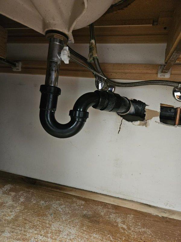 Responded to upstairs bathroom sink drain clog that persisted despite homeowner's prior attempts to clear the blockage by removing and cleaning the P-trap and applying chemical drain cleaner four days prior. Upon arrival, inspected the sink drain system and P-trap assembly beneath the fixture, confirming proper reinstallation of the trap components. Determined that the obstruction was located beyond the P-trap in the branch drain line. Utilized mechanical drain cleaning equipment to access and clear the blockage in the drain line extending from the fixture. Successfully restored full drainage flow to the bathroom sink, with water draining freely and completely.