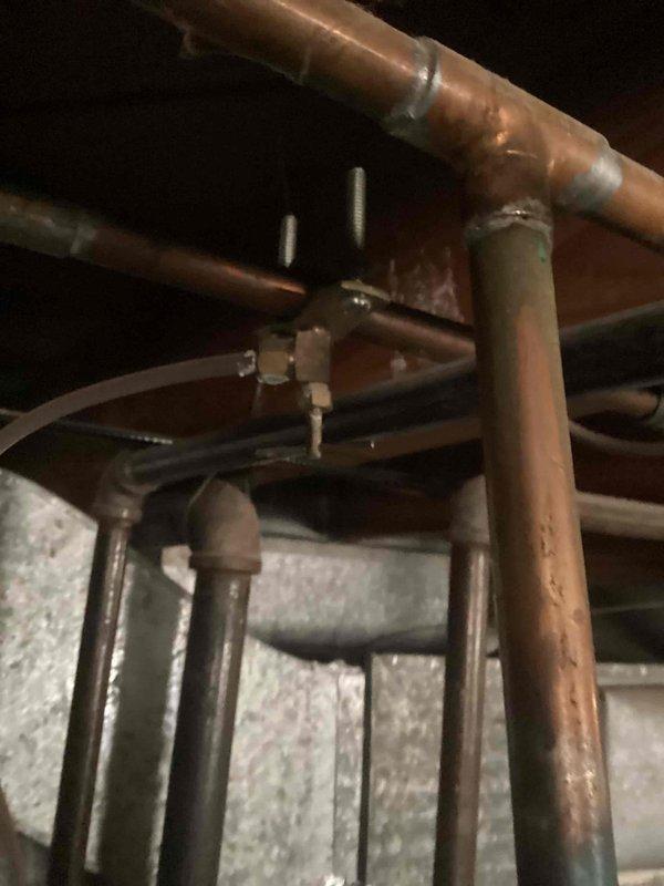 Responded to recall for ongoing condensation issue at furnace location. Inspected copper piping system and connections in attic space where moisture was reported originating from top of furnace, documented existing infrastructure including horizontal and vertical pipe runs, compression fittings, and surrounding insulation for further evaluation and coordination with team to determine source of condensation and appropriate remediation steps.