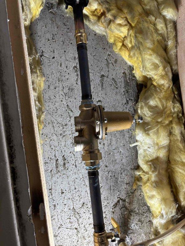 Responded to no hot water issue at basement shower. Upon inspection, determined shower valve was faulty and preventing hot water flow to fixture while rest of house had proper hot water supply. Replaced defective shower valve with new brass valve assembly, reconnecting supply lines and securing installation between floor joists. During troubleshooting process, main water shutoff to house was required, at which time discovered minor leak at main shutoff valve. Tested system after valve replacement and confirmed hot water now flowing properly to basement shower. All connections secured and installation verified operational.