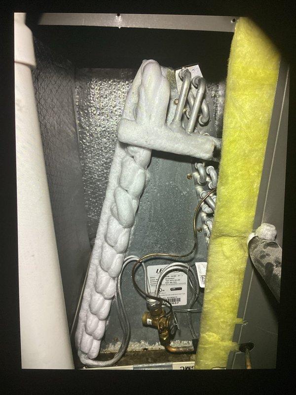 Responded to service call for single-zone residential HVAC system with frozen evaporator coil causing inadequate cooling. Upon arrival, confirmed coil had thawed sufficiently to proceed with diagnostic evaluation. Inspected furnace located in basement and outdoor condensing unit at rear of property. Examined refrigerant lines, insulation integrity, and control components within air handler cabinet. Measured supply air temperature at 79.1°F, confirming insufficient cooling capacity. Evaluated potential causes of coil freezing including restricted airflow, low refrigerant charge, and system operation parameters. Documented system conditions with thermal readings and visual inspection of refrigerant line connections, insulation wrapping, and control wiring. Coordinated service timing with homeowner via text communication to ensure evaporator coil had adequate time to defrost before technician arrival, preventing damage to compressor and allowing proper system assessment.