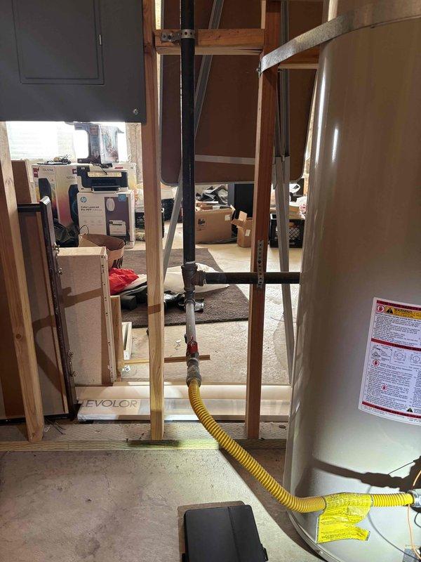 Responded to no hot water complaint on 25+ year old tanked water heater in basement. Upon inspection, diagnosed failed gas valve on unit that had exceeded its expected service life. Documented existing installation with yellow flexible gas line connection and current gas control assembly condition. Recommended full water heater replacement due to age and component failure.