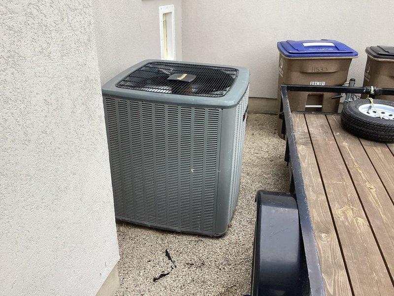 Responded to report of wheezing system and improperly mounted filter on 5-year-old single-zone HVAC system with ground-mounted condenser and basement furnace. Inspected return air grille showing dust accumulation on louvered slats and verified outdoor condenser unit condition on cracked concrete pad. Corrected air filter installation and addressed airflow restriction causing abnormal system noise.