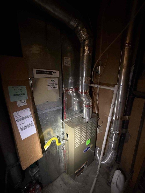 Completed full residential HVAC system installation featuring a Carrier furnace unit with associated ductwork, venting, and drainage systems. Installation included rigid and flexible metal ductwork configuration, black exhaust piping, white PVC condensate drain lines, and all necessary electrical connections. System was installed in utility area, tested, and left operational per specifications.