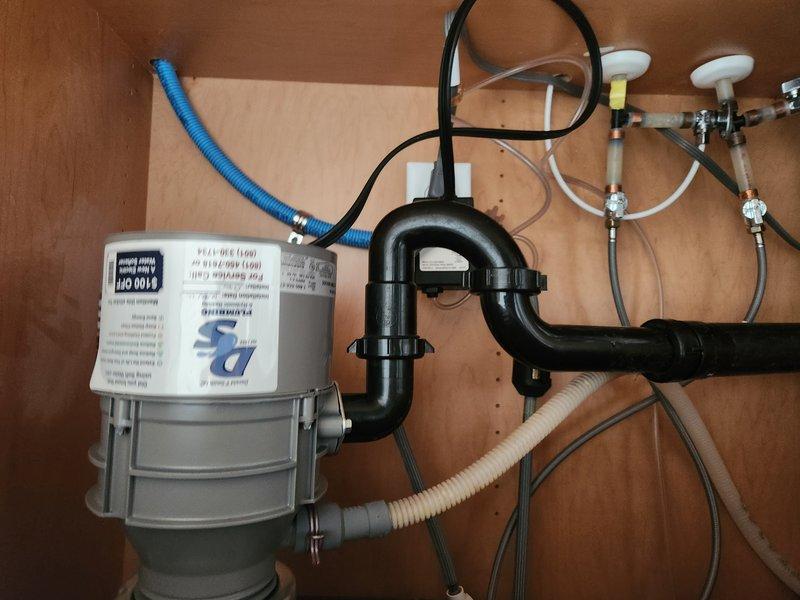 Responded to service call for inoperative garbage disposal unit at residential property. Upon arrival, accessed under-sink cabinet and inspected 4-year-old disposal unit and associated plumbing connections. Customer reported disposal would not turn on and that attempts to manually rotate the impeller using the hex wrench resulted in the entire unit rotating, indicating mounting failure. Diagnosed failed mounting assembly where disposal had separated from sink flange connection. Evaluated P-trap configuration, drain connections, and electrical supply to unit. Determined disposal required replacement due to compromised mounting system and age of equipment. Disconnected existing disposal from electrical supply, P-trap drain line, and dishwasher drain connection. Removed failed unit from sink mounting assembly. Installed new garbage disposal unit with proper mounting ring and support assembly. Reconnected P-trap, dishwasher drain line with appropriate air gap configuration, and restored el