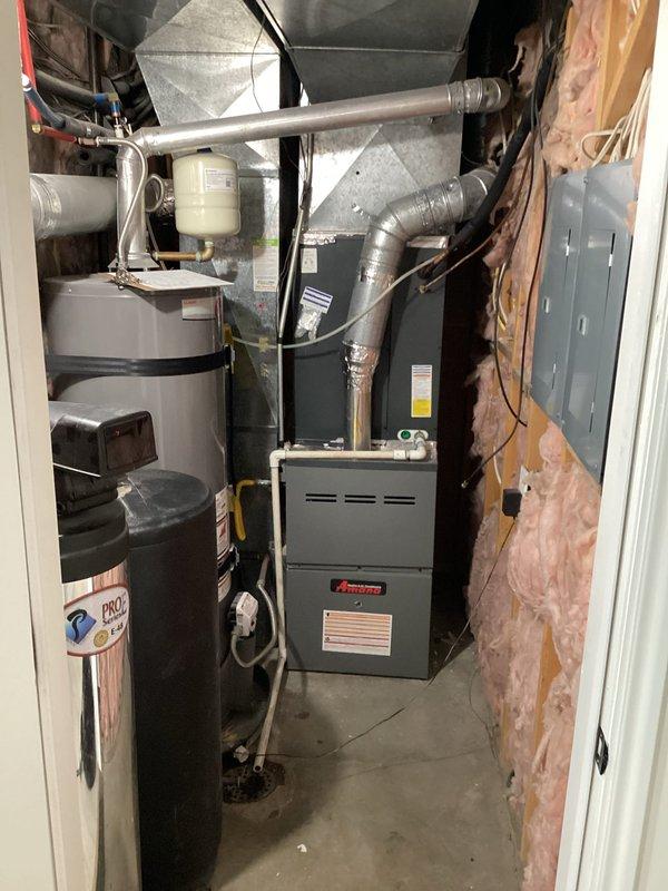 Responded to reported system wheezing and filter mounting concerns on a 5-year-old residential HVAC system with furnace located in basement and AC unit on ground level. Performed diagnostic evaluation and identified multiple systemic issues including oversized equipment, undersized ductwork, and inadequate return air configuration. Documented existing Amana furnace installation with visible condensate drainage system and metallic flex duct connections in unfinished basement utility area. Provided comprehensive system assessment and replacement options to address airflow deficiencies and equipment sizing concerns.