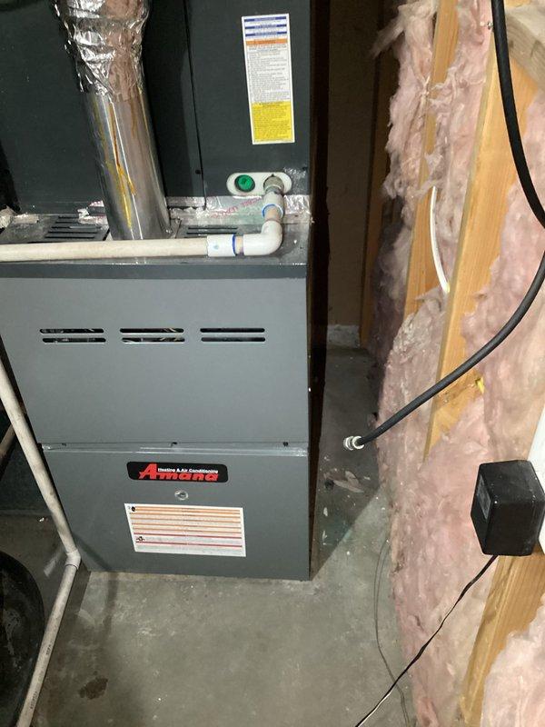 Responded to reported system wheezing and filter mounting concerns on a 5-year-old residential HVAC system with furnace located in basement and AC unit on ground level. Performed diagnostic evaluation and identified multiple systemic issues including oversized equipment, undersized ductwork, and inadequate return air configuration. Documented existing Amana furnace installation with visible condensate drainage system and metallic flex duct connections in unfinished basement utility area. Provided comprehensive system assessment and replacement options to address airflow deficiencies and equipment sizing concerns.