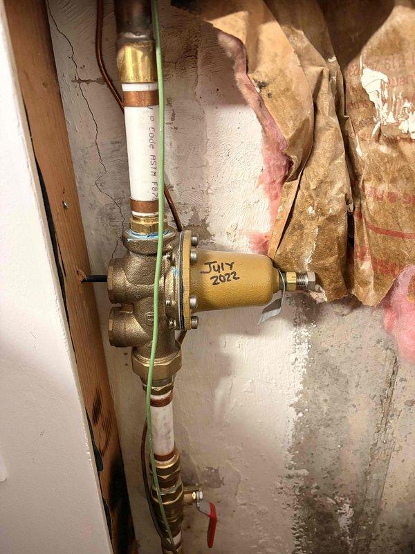 Evaluated existing 2010 tanked water heater installation in basement utility area with no current operational issues. Inspected GE brand unit, copper supply lines, brass shut-off valves, pressure regulator dated July 2022, and PVC drain piping configuration. Discussed replacement options including both traditional tanked and tankless water heater systems with homeowner due to age of existing equipment approaching end of expected service life.