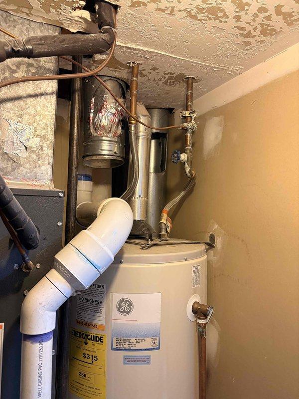 Evaluated existing 2010 tanked water heater installation in basement utility area with no current operational issues. Inspected GE brand unit, copper supply lines, brass shut-off valves, pressure regulator dated July 2022, and PVC drain piping configuration. Discussed replacement options including both traditional tanked and tankless water heater systems with homeowner due to age of existing equipment approaching end of expected service life.