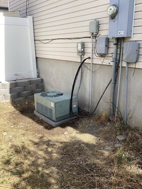Responded to service call for 25-year-old residential HVAC system experiencing freezing issues after unauthorized refrigerant addition. Performed comprehensive diagnostic evaluation of single-unit system with outdoor condenser located in backyard and furnace in basement. Inspection revealed failed blower motor and significant refrigerant loss in the system. Documented equipment condition through photographic evidence showing exterior-mounted condenser unit with associated electrical components and service disconnect. Provided technical assessment and presented repair options including blower motor replacement and complete refrigerant recharge to restore proper system operation.