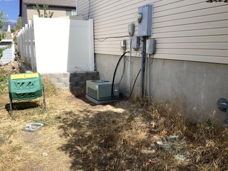 Responded to service call for 25-year-old residential HVAC system experiencing freezing issues after unauthorized refrigerant addition. Performed comprehensive diagnostic evaluation of single-unit system with outdoor condenser located in backyard and furnace in basement. Inspection revealed failed blower motor and significant refrigerant loss in the system. Documented equipment condition through photographic evidence showing exterior-mounted condenser unit with associated electrical components and service disconnect. Provided technical assessment and presented repair options including blower motor replacement and complete refrigerant recharge to restore proper system operation.
