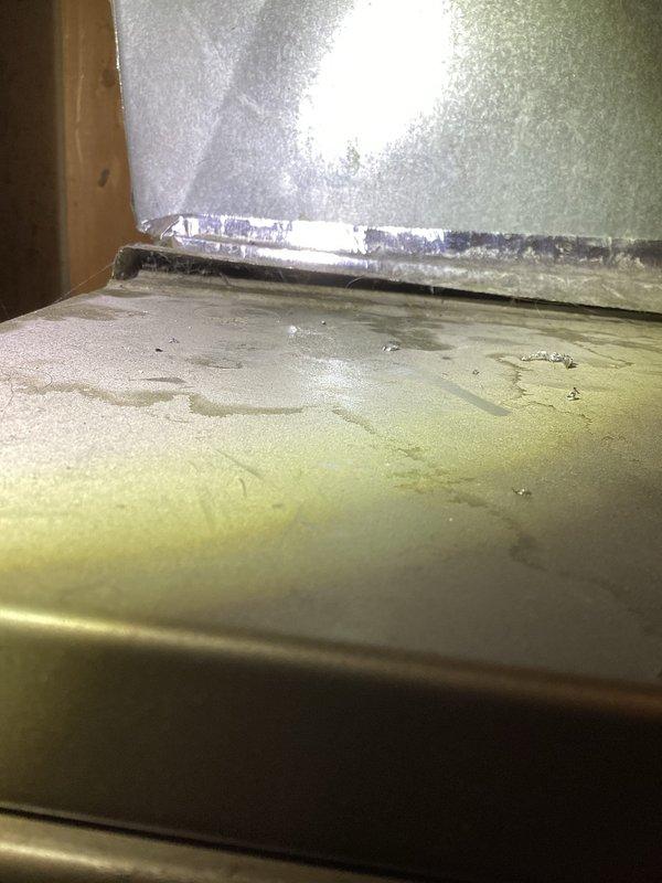 Responded to warranty callback for AC unit not performing properly following recent maintenance on 2-year-old system. Upon inspection, discovered significant moisture accumulation in drain pan with evidence of standing water, water staining, and possible microbial growth along evaporator coil base and drain pan edges. Tested capacitor with multimeter and found 7.5μF capacitor reading outside acceptable tolerance range. Replaced defective capacitor with new 7.5μF 370VAC unit and cleared drain line obstruction causing water backup in air handler. Verified proper condensate drainage, confirmed system cooling operation, and documented moisture damage for customer awareness.