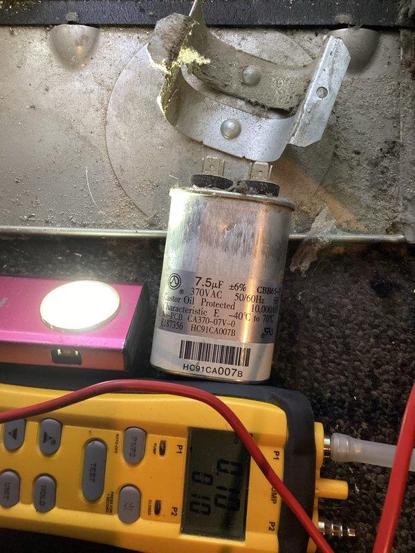 Responded to warranty callback for AC unit not performing properly following recent maintenance on 2-year-old system. Upon inspection, discovered significant moisture accumulation in drain pan with evidence of standing water, water staining, and possible microbial growth along evaporator coil base and drain pan edges. Tested capacitor with multimeter and found 7.5μF capacitor reading outside acceptable tolerance range. Replaced defective capacitor with new 7.5μF 370VAC unit and cleared drain line obstruction causing water backup in air handler. Verified proper condensate drainage, confirmed system cooling operation, and documented moisture damage for customer awareness.