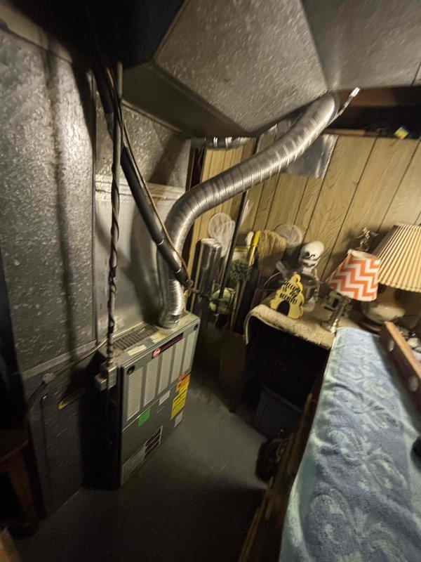 Responded to no-cooling call on a 25-year-old residential HVAC system with AC unit located at rear of property and furnace in basement. Upon diagnostic evaluation, determined system had complete refrigerant loss and was operating beyond serviceable life expectancy. Assessed existing equipment condition, ductwork configuration, and installation requirements. Provided comprehensive estimate for full system replacement, presenting options ranging from standard efficiency to high-efficiency equipment configurations. Documented existing basement furnace installation with metallic ductwork and insulation setup for replacement planning purposes.