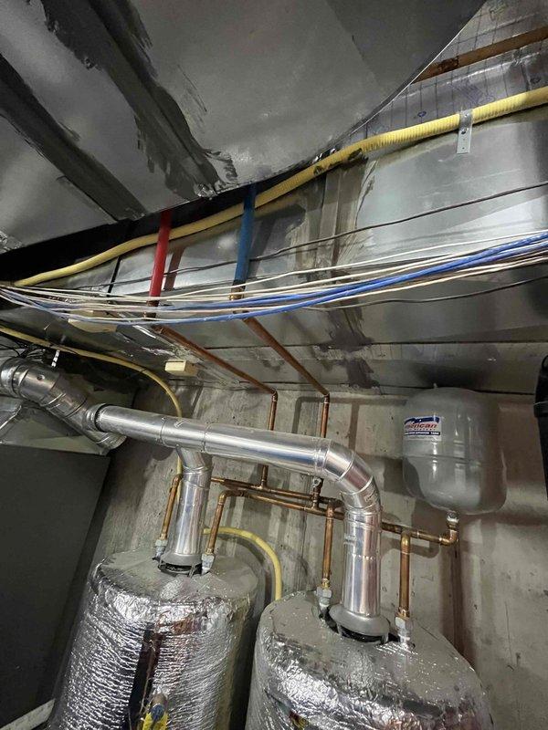 Performed routine maintenance flush on tanked water heater system. Inspected dual water heater installation with reflective insulation wrapping, verified all connections, valves, and piping for proper operation. Confirmed expansion tanks, copper supply lines, and associated HVAC ductwork in mechanical room are functioning correctly with no visible leaks or issues detected.