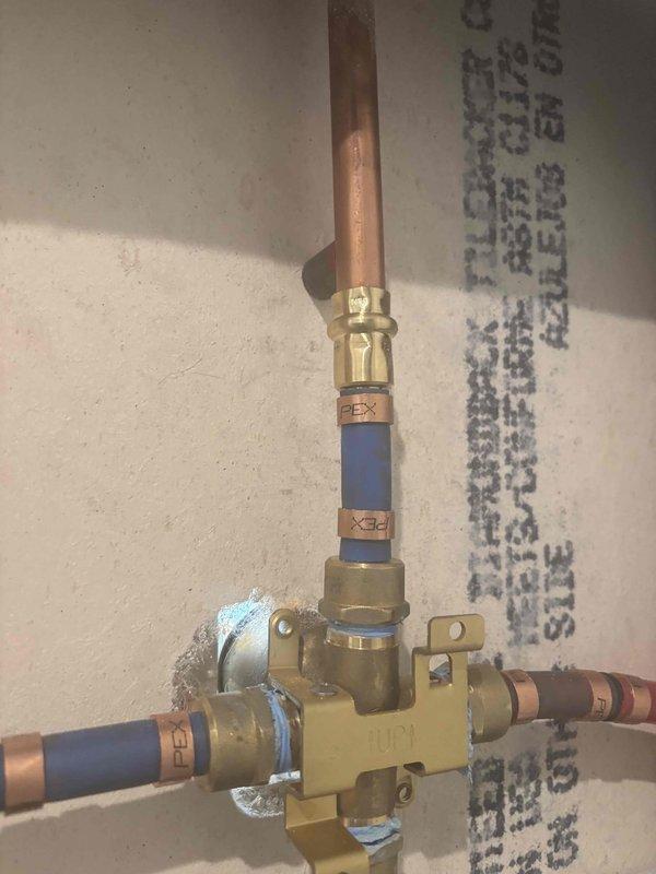 Responded to callback for damaged valve housing that was leaking following previous repair attempt at main floor bathroom shower valve. Repaired compromised brass manifold assembly and compression fittings where damage had occurred during initial service. Installed new PEX connections to integrate with existing copper supply lines, ensuring proper sealing at all junction points. Verified system integrity and confirmed no active leaks at valve housing or connection points upon completion.