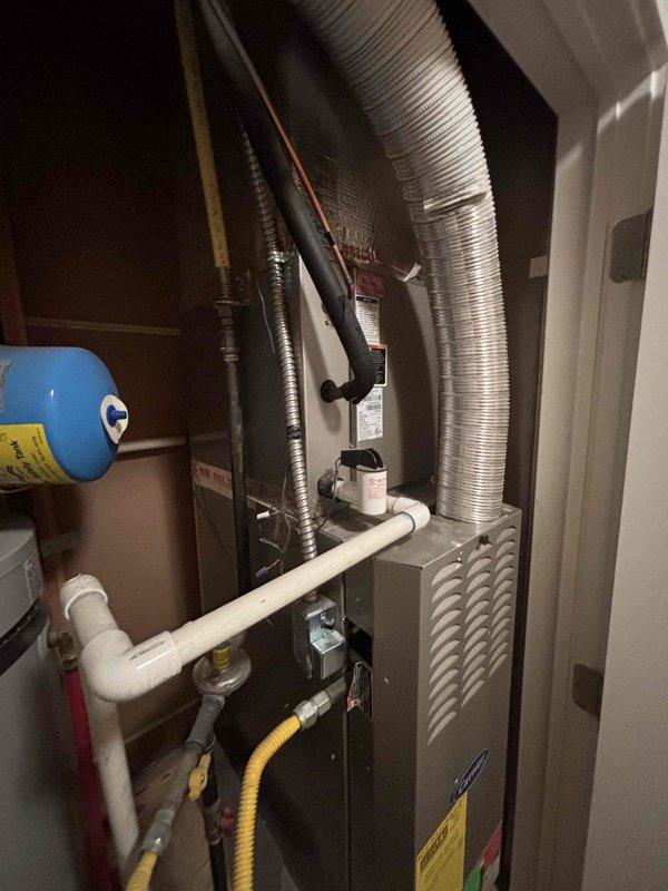 Evaluated 30-year-old residential HVAC system experiencing cooling failure with air handler operational but no refrigeration. Documented existing equipment configuration including furnace, ductwork, gas line, PVC drainage, and associated mechanical components in utility closet. Provided complete system replacement estimate due to age of equipment and loss of cooling capacity.
