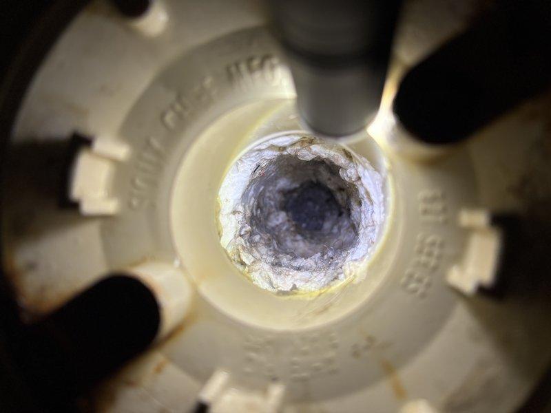 Responded to a completely backed-up basement shower drain. Upon inspection, found significant mineral deposits, soap scum, and sediment buildup within the SCH 40 PVC drain assembly, causing severe flow restriction. Cleared the obstruction and restored proper drainage to the fixture.